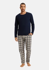 Marineblauw overhemd met lange mouwen, gecombineerd met beige geruite pyjamabroek met blauwe en zwarte accenten, gemaakt van zacht materiaal voor comfort.