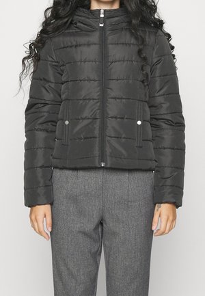 Doudoune noire avec une fermeture éclair à l'avant, des coutures horizontales et un col haut. Dispose de poches latérales et d'une texture lisse et brillante.