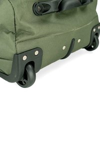 Bolsa enrollable de tela verde con una base resistente, equipada con ruedas negras lisas y detalles metálicos. Material duradero con esquinas reforzadas.