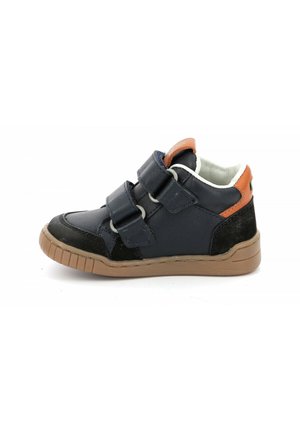 Zapatilla alta de color azul marino con correas de Velcro, acentos marrones, punta texturizada de color negro y suela de goma. Forro interior suave visible.