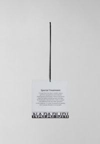 Clear plastic care label with black text. Features "NAPA PURI" in bold print at the bottom, attached by a black string.