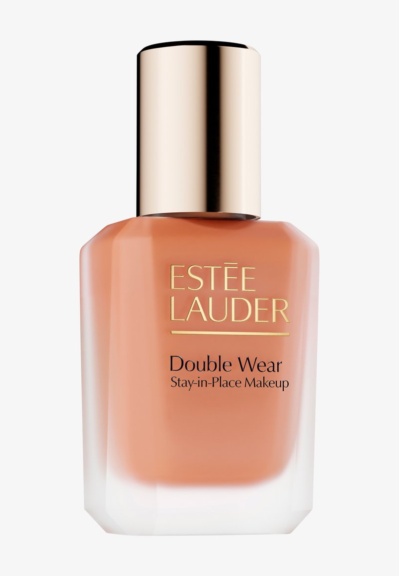 Bouteille en verre à base ronde et forme carrée, avec un bouchon doré brillant. Liquide orange étiqueté "Double Wear Stay-in-Place Makeup".