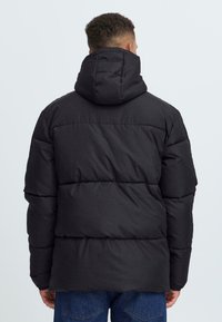Jachetă puffer neagră cu glugă, design matlasat și umplutură groasă. Croială standard și detalii de cusătură vizibile pe spate.