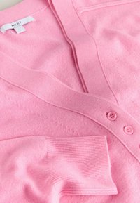 Rosa Strickjacke aus weichem Material, mit V-Ausschnitt, gerippten Bündchen und drei rosa Knöpfen. Das Design umfasst subtile Texturdetails.