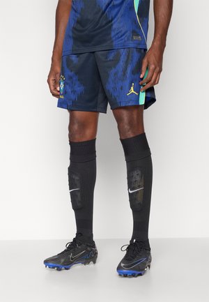 Stroje piłkarskie Nike z granatową koszulką z pionowymi niebieskimi paskami, dopasowanymi szortami, czarnymi wysokimi getrami i czarnymi korkami z niebieskimi akcentami.