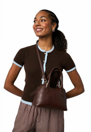 Braune Lederhandtasche mit geschwungenen Griffen, glatter Textur und Reißverschluss, kombiniert mit einem dunkelbraunen, gerippten Hemd mit hellblauen Akzenten.