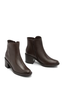 Botine din piele maro, cu un finisaj lucios, fermoar lateral și un design cu toc pătrat. Textură netedă și stil minimal.