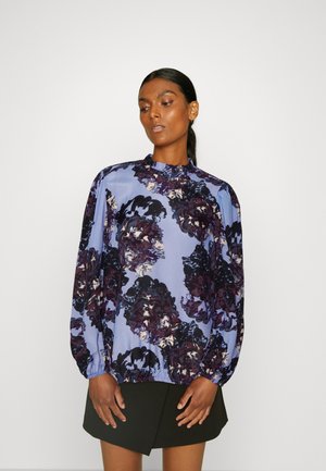 Μακρυμάνικη μπλούζα σε ανοιχτό μπλε χρώμα με σκούρο florale σχέδιο. Διαθέτει ρυτιδωτό γιακά και συγκεντρωμένα μανίκια. Λείο, ελαφρύ ύφασμα.