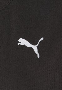 Černá atletická látka s texturovaným povrchem obsahuje bílý logo Puma zobrazující skákající kočku.