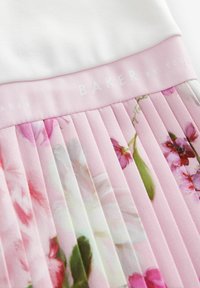 Jupe plissée avec un design floral rose, arborant une taille blanche avec "BAKER BY TED" imprimé en texte clair. Tissu lisse et léger.