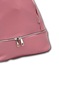 Sac en cuir rose avec une texture lisse, doté d'une fermeture éclair en métal et de coutures contrastantes. Forme arrondie avec une poche latérale.