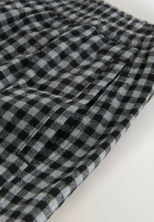 Czarny i szary materiał w kratę z wzorem houndstooth, o miękkiej teksturze i plisowanym designie, widok pod kątem ukazujący kieszenie.