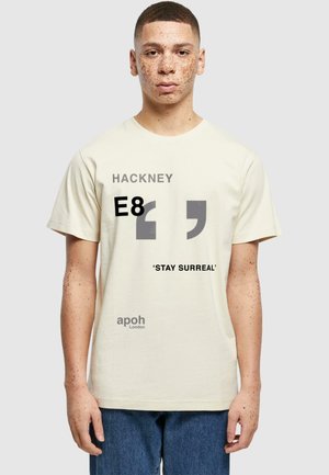 Cremefarbiges Baumwoll-T-Shirt mit grafischem Text: "HACKNEY E8" und "'STAY SURREAL. apoh London" in verschiedenen Schriftarten und Farben.