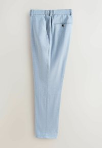 Pantalon bleu clair sur mesure avec une ceinture élastique et une poche arrière unique à fermeture par bouton, posé à plat sur une surface claire.