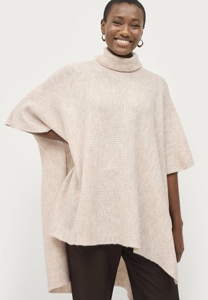 Knit poncho in soft beige with a high turtleneck, short sleeves, and asymmetric hem. Features ribbed texture and a relaxed fit.