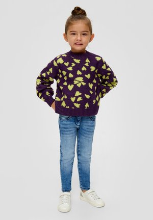 Paarse gebreide trui met groen hart patroon, ronde hals en lange mouwen, gecombineerd met lichtblauwe jeans en witte sneakers.