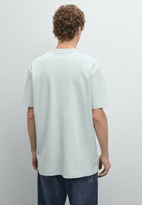 Světle mátově zelené oversized tričko vyrobené z měkké látky, s kulatým výstřihem, krátkými rukávy a uvolněným střihom.