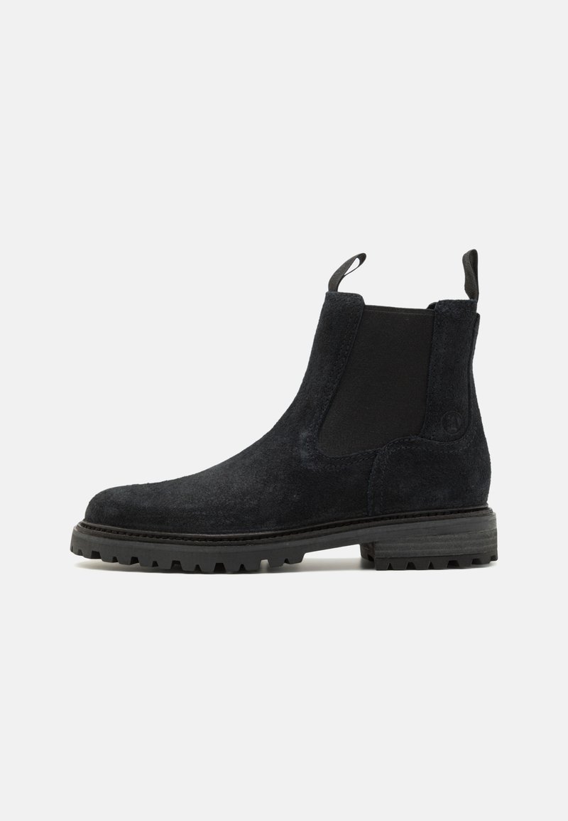 Bottines Chelsea en suede noir avec panneaux élastiques latéraux, tirant et semelle en caoutchouc robuste dotée de profondes rainures pour une traction optimale.