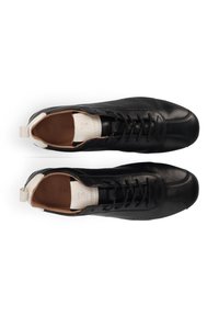 Schwarze Leder Sneaker mit glatter Textur, Schnürdesign und kontrastierendem, cremefarbenem Fersenstück mit eingeprägtem Logo.