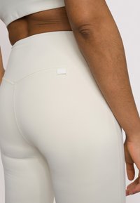 Leggings in een lichte creme kleur, met een soepel, rekbaar materiaal, platte naden en een discreet logo-label op de achterkant van de tailleband.