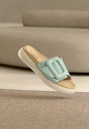 Sandale bleu clair à enfiler avec une tige rembourrée et une grande boucle surdimensionnée remarquable. Finition en cuir lisse et semelle en caoutchouc blanche.