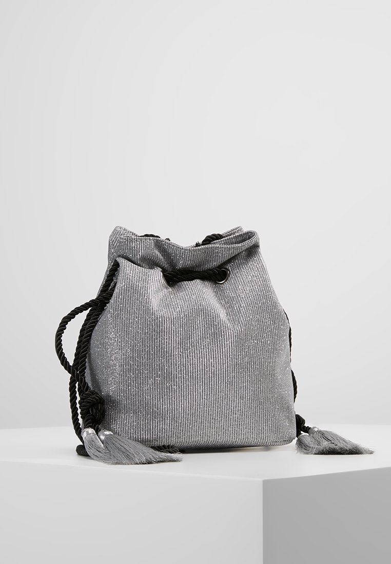 Silberne Zugtasche aus strukturiertem Stoff, mit schwarzen geflochtenen Trägern und Quastenakzenten. Runde Form mit einem weichen, lässigen Design.