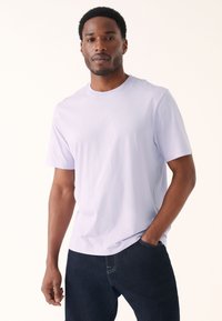 Vaalean violetti lyhythihainen t-paita, jossa pyöreä kaula-aukko, valmistettu pehmeästä kankaasta. Yhdistetty tummansinisiin farkkuihin, joissa on taskudetalji.