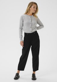 Light gray button-up cardigan with ribbed cuffs, paired with high-waisted black trousers featuring front pleats and black loafers.