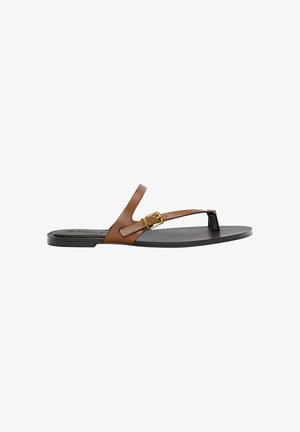 Tan leather thong sandal with a gold buckle detail, flat black sole, and minimalistic design, featuring a smooth texture.