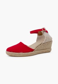Alpargatas de cuña de lona roja con suela de yute trenzado y correa para el tobillo. Tejido beige texturizado en el talón trasero. Diseño elegante con puntera redondeada.