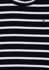 Suéter a rayas con franjas alternas en azul marino y blanco, hecho de tejido acanalado, con un pequeño logo en el pecho.