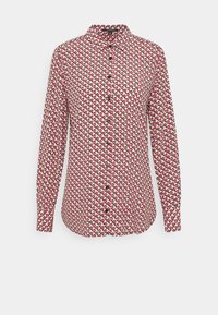 Chemise à manches longues blanche avec un motif circulaire rouge et noir, dotée d'un devant boutonné et d'un petit col. Fabriquée à partir d'un tissu lisse.