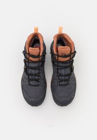 Scarpe da ginnastica grigio scuro con dettagli arancioni, caratterizzate da una tomaia testurizzata, collare imbottito e lacci neri. Suola robusta per una buona trazione.