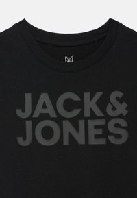 Fekete pamut póló kerek nyakkivágással, a mellkasán kiemelkedő fekete "JACK & JONES" felirattal, a galléron pedig egy kis logócímkével.