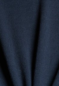 Tissu en tricot bleu marine foncé avec une texture douce, présentant des motifs de points verticaux visibles et des plis.