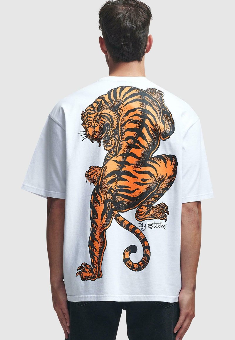 Hvit oversized t-skjorte med et stort, detaljert grafisk motiv av en oransje og svart tiger på baksiden. Korte ermer og rund hals.