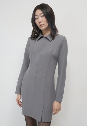 Abito grigio a maniche lunghe con colletto, zip frontale e spacchi laterali. Realizzato in tessuto liscio con una silhouette aderente.