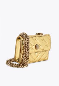 Złota torebka z lakierowanej skóry o pikowanym wzorze, wyposażona w łańcuszkowy pasek i zatrzask z ozdobnym emblematem na przodzie.