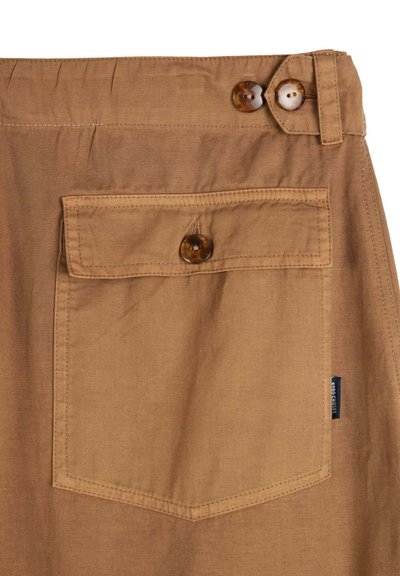 Tissu beige avec une poche à rabat boutonnée et deux boutons marron sur la ceinture, comprenant une petite étiquette de marque sombre sur le côté.