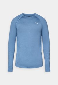 Lys blå langermet treningstrøye, rund hals, teksturert stoff, med hvit logo på brystet og ventilasjonsdetaljer på siden.