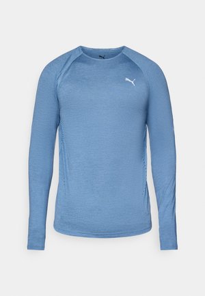 Lichtblauw langemouwen sportshirt, ronde hals, met gestructureerde stof, voorzien van een wit logo op de borst en ventilatiedetails aan de zijkanten.