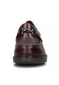 Mocassino in pelle marrone con finitura lucida, caratterizzato da una decorativa accentatura in catena metallica nera sulla tomaia e una sottile suola a piattaforma.