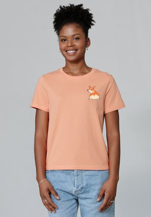 Perzikkleurig katoenen T-shirt met korte mouwen, voorzien van een corgi-illustratie op de linkerborst. Casual pasvorm, ronde halslijn en zachte textuur.