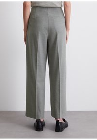 Grå vida byxor med en texturerad finish, med hög midja och en bakficka, parat med svarta skor.