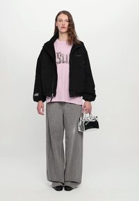 Black oversized jacket, pink graphic t-shirt, gray wide-leg pants, shiny silver handbag, and black shoes. Minimalist design and casual style.