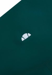 Ciemnozielony materiał o gładkiej fakturze z białym logo. Projekt jest minimalistyczny z subtelnymi detalami przeszycia.