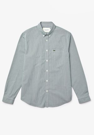 Chemise à manches longues à carreaux gris et blancs avec un col boutonné, dotée d'une poche poitrine et d'un petit logo vert sur la poche.