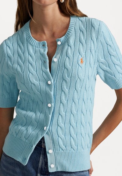 Hellblauer Strickcardigan mit kurzen Ärmeln, runder Ausschnitt und weißen Knopfverschlüssen. Hat ein kleines oranges Logo auf der Brust.