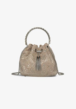 Beige emmer tas met perforaties, metallic hardware, een kettinghandvat en een kwastaccent. Zachte textuur met een trekkoordsluiting.