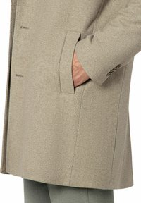 Beiger, strukturierter Wollmantel mit schmaler Passform, Reverskragen und Seitentaschen. Sichtbare Nähte und Knopfakzente in der Nähe der Manschette.